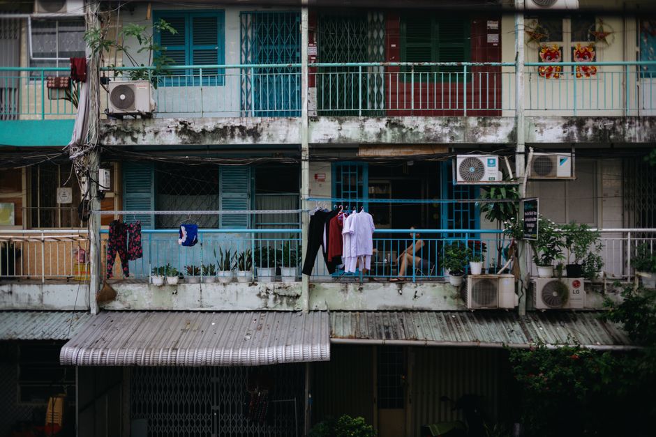 A residential balcony with drying laundry, plants, and air conditioning units.