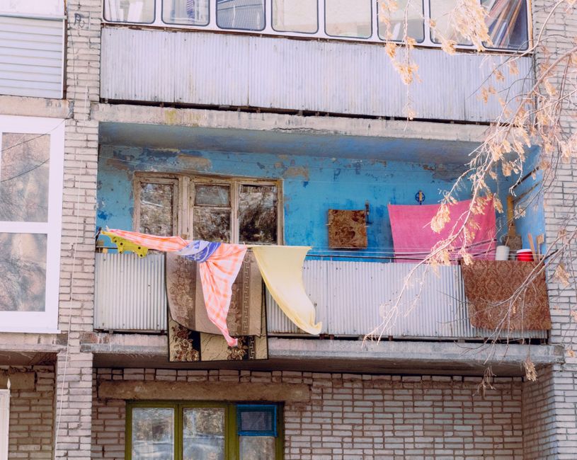 Vibrant textiles drying on a rustic urban apartment balcony.