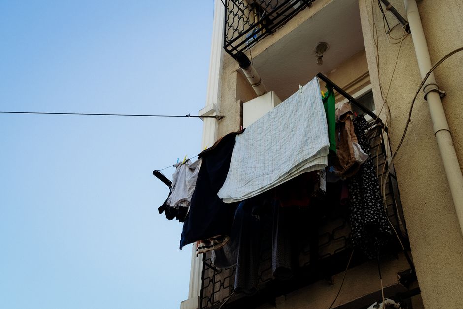 Clothes drying on a balcony line against a clear sky, capturing urban lifestyle.